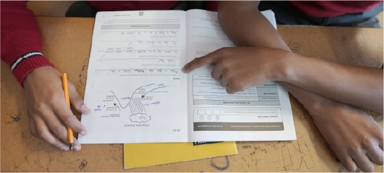 Hands working through exercises in an open workbook